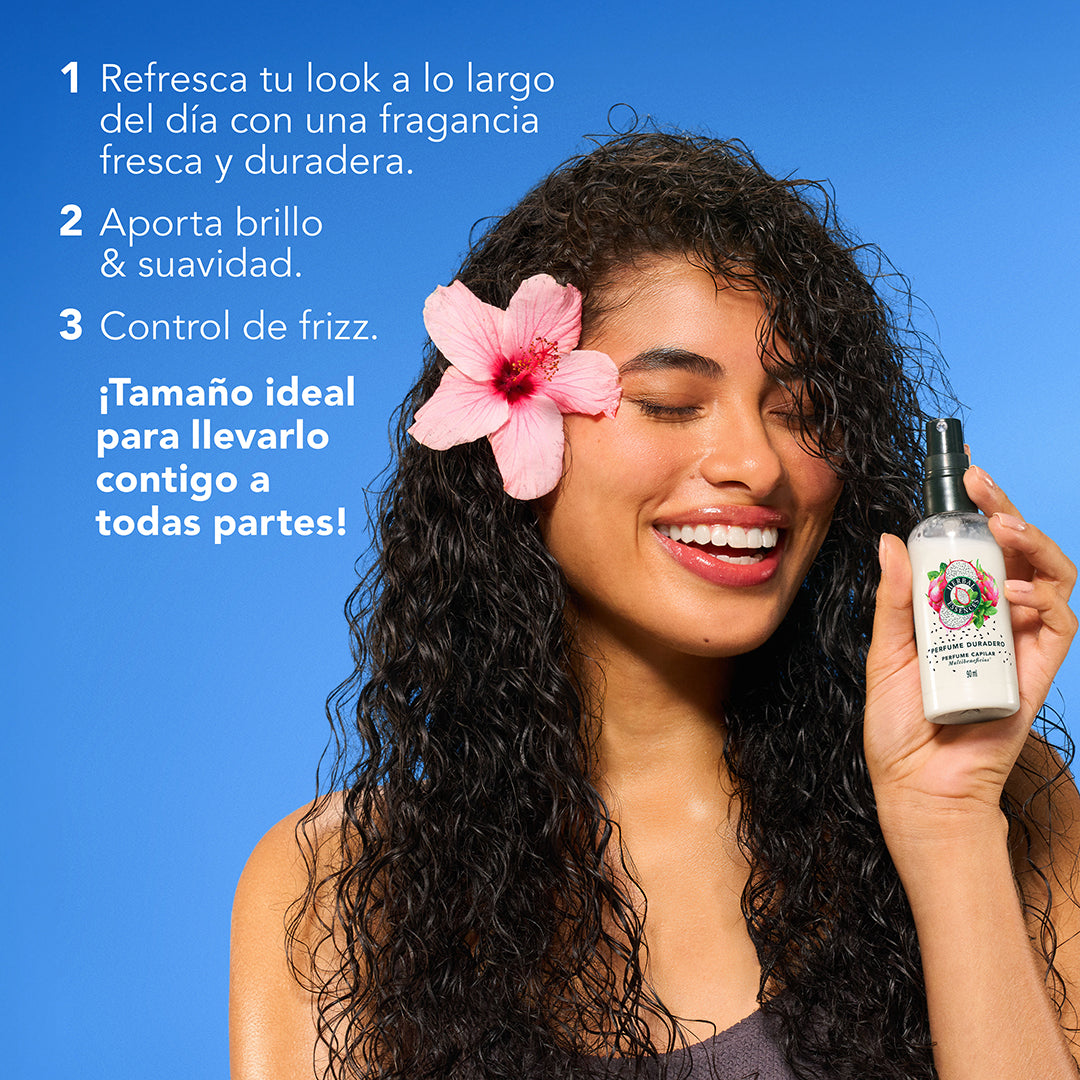 Mujer con cabello rizado y flor en el cabello sosteniendo Perfume Capilar Herbal Essences Pitahaya y Menta con texto multibeneficios brillo suavidad control de frizz tamaño ideal para llevarlo a todas partes