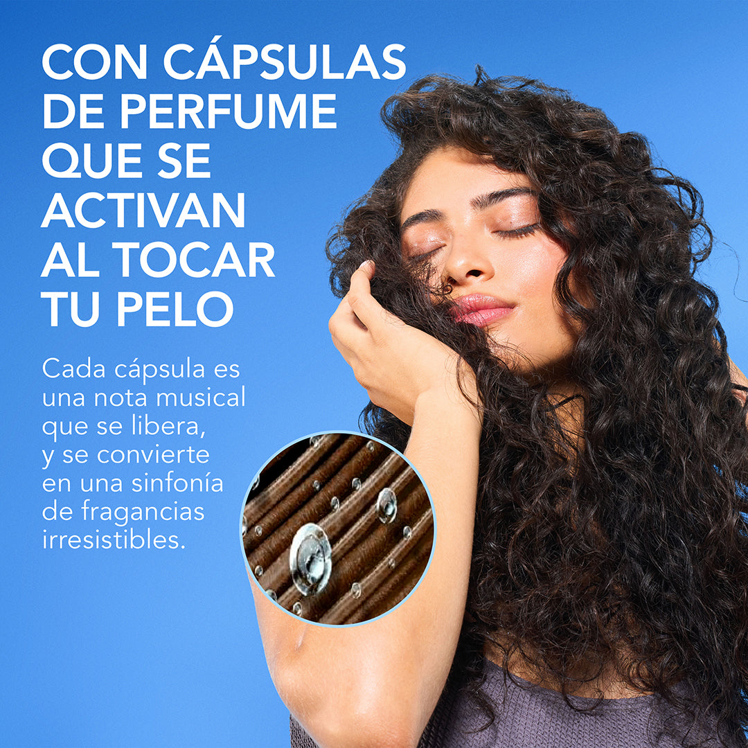 Mujer con cabello rizado tocándose el pelo con detalle de cápsulas de perfume y texto Con Cápsulas de Perfume que se activan al tocar tu pelo sinfonía de fragancias irresistibles
