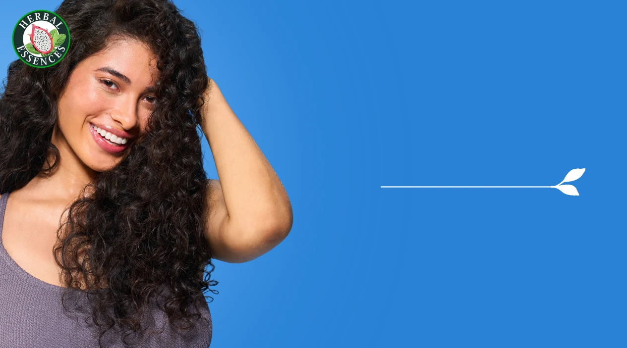 Mujer tocando su cabello con Crema para Peinar Herbal Essences Pitahaya y Menta con texto No Necesita Enjuague aplica en cabello húmedo o seco
