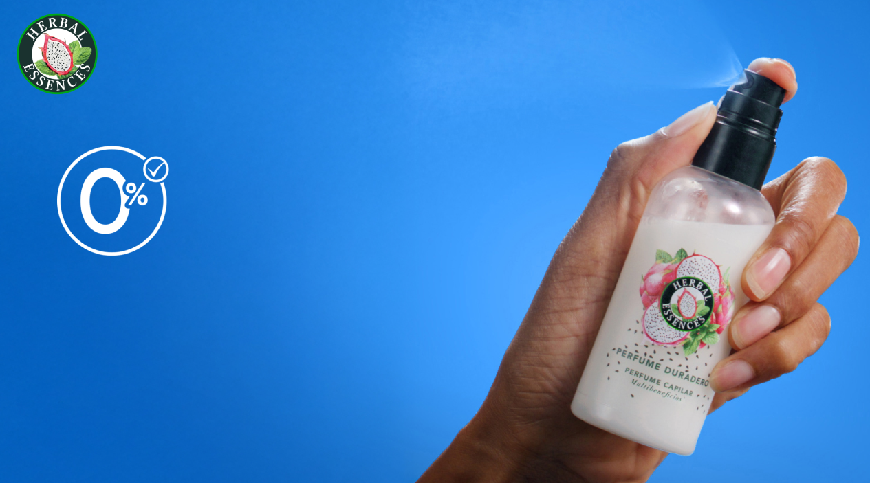 Mano sosteniendo Perfume Capilar Herbal Essences Pitahaya y Menta con texto 0% Alcoholes Secantes aroma fresco todo el día cabello brillante con frizz controlado